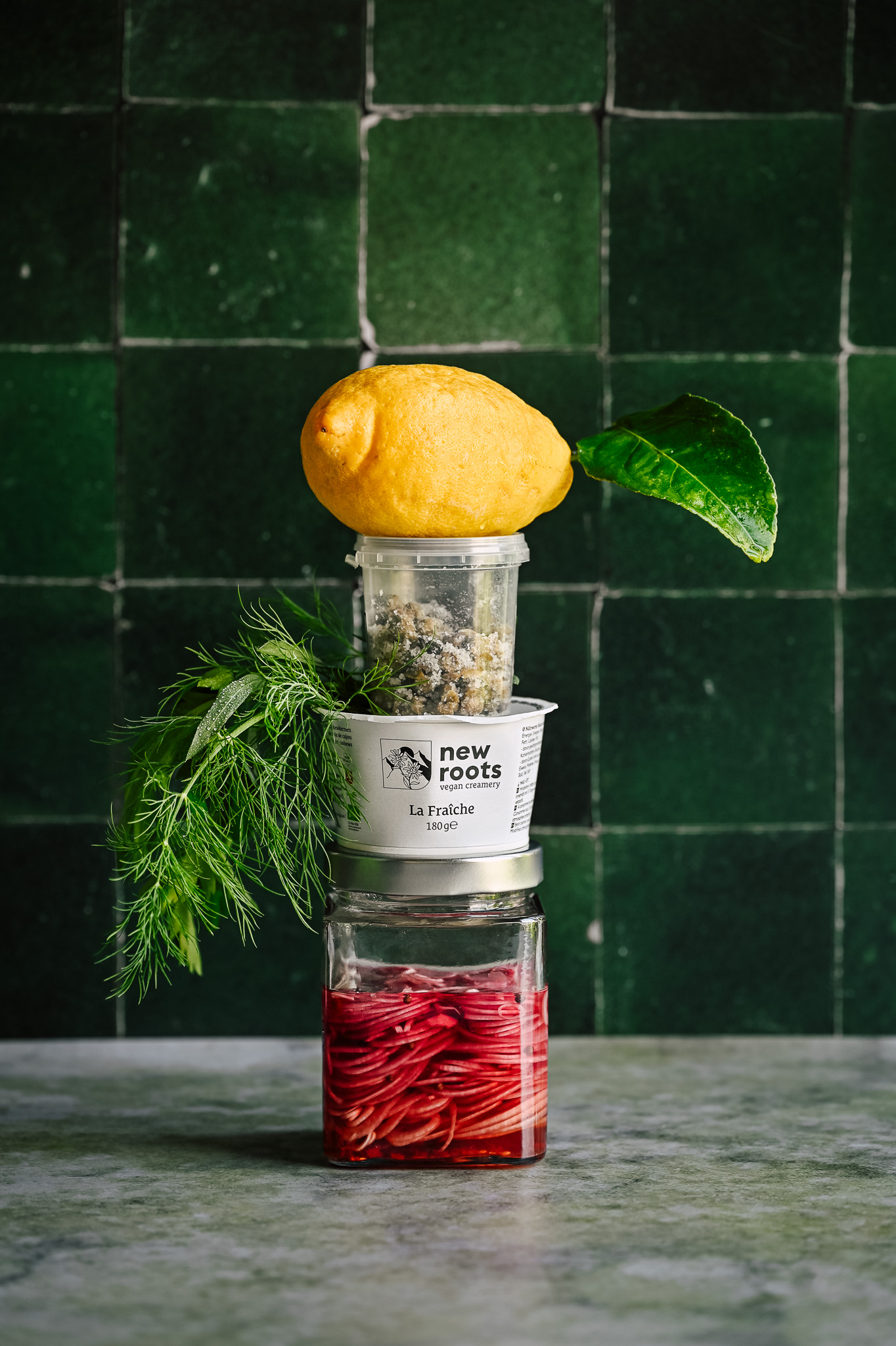 Still life stack with new roots fraîche, pickled onions, lemon and capers