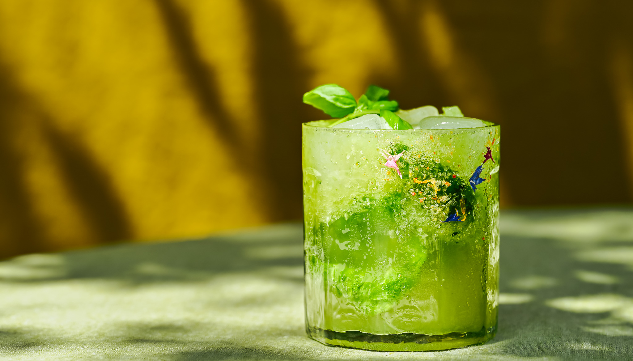 Mocktail with cucumbers and basil, chili salt and edible blossoms