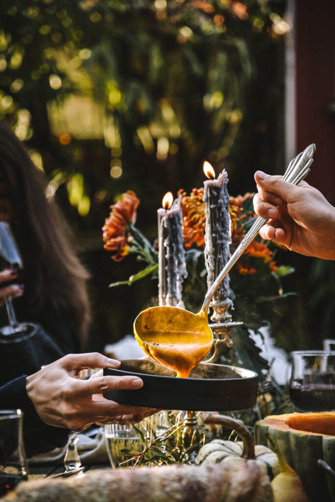 Pumpkin soup served with candles and flowers in the background