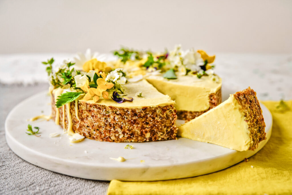 Raw protein-lemon cake with edible blossoms and crunchy crust